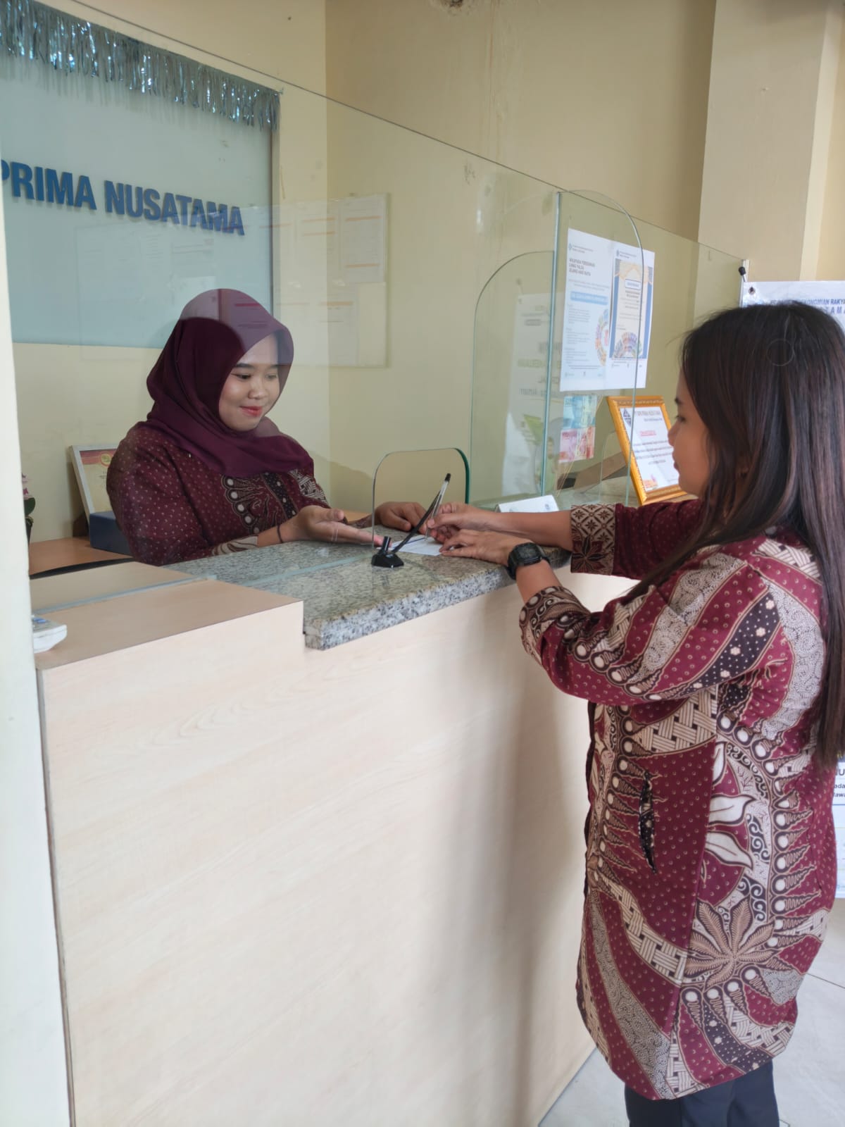 Teller BPR Prima Nusatama melayani nasabah yang melakukan setoran penempatan dana.